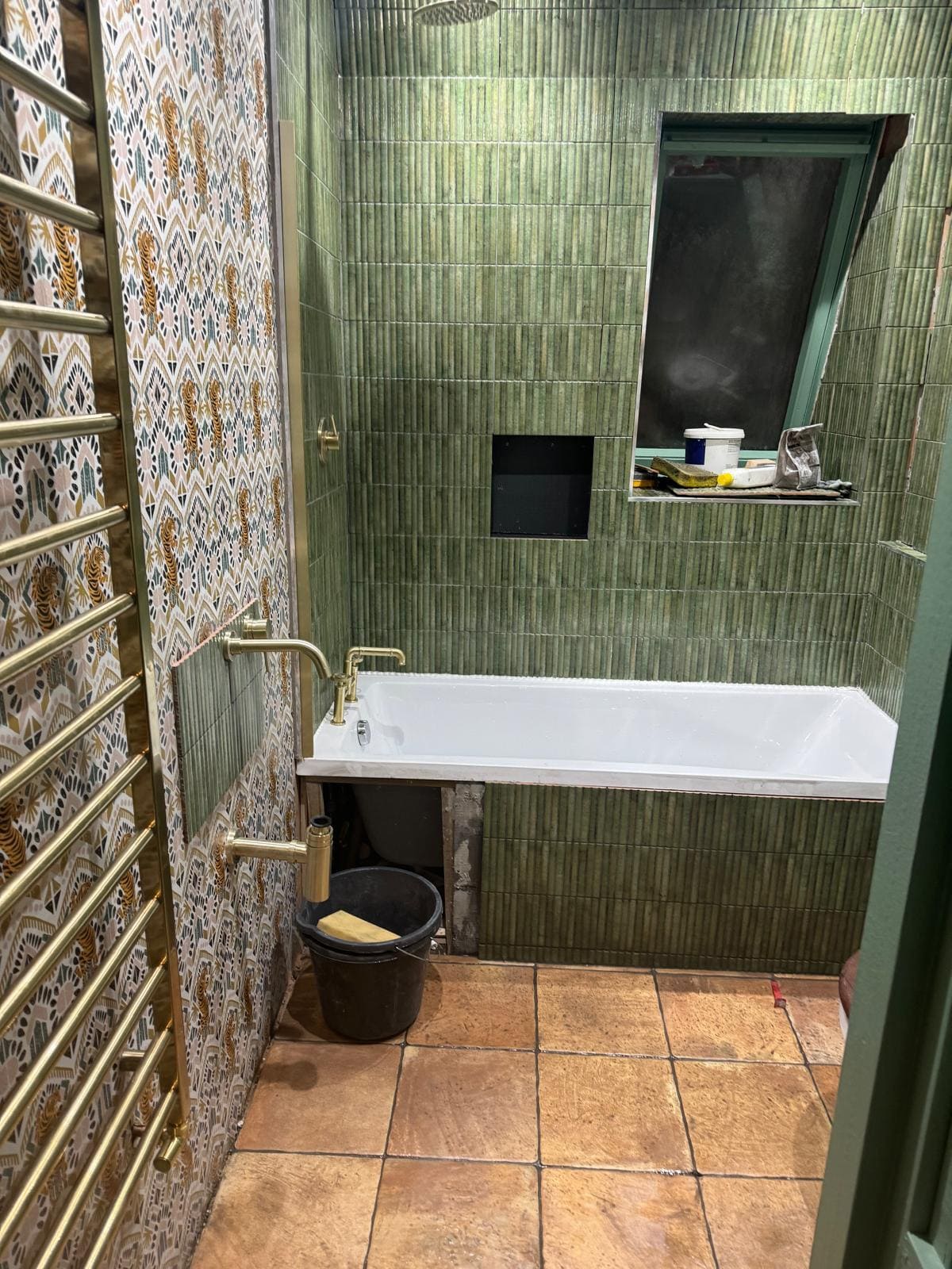 London bathroom refurbishment with green fluted tiles, brass heated towel rail and inset shower niche by Refurb Squad