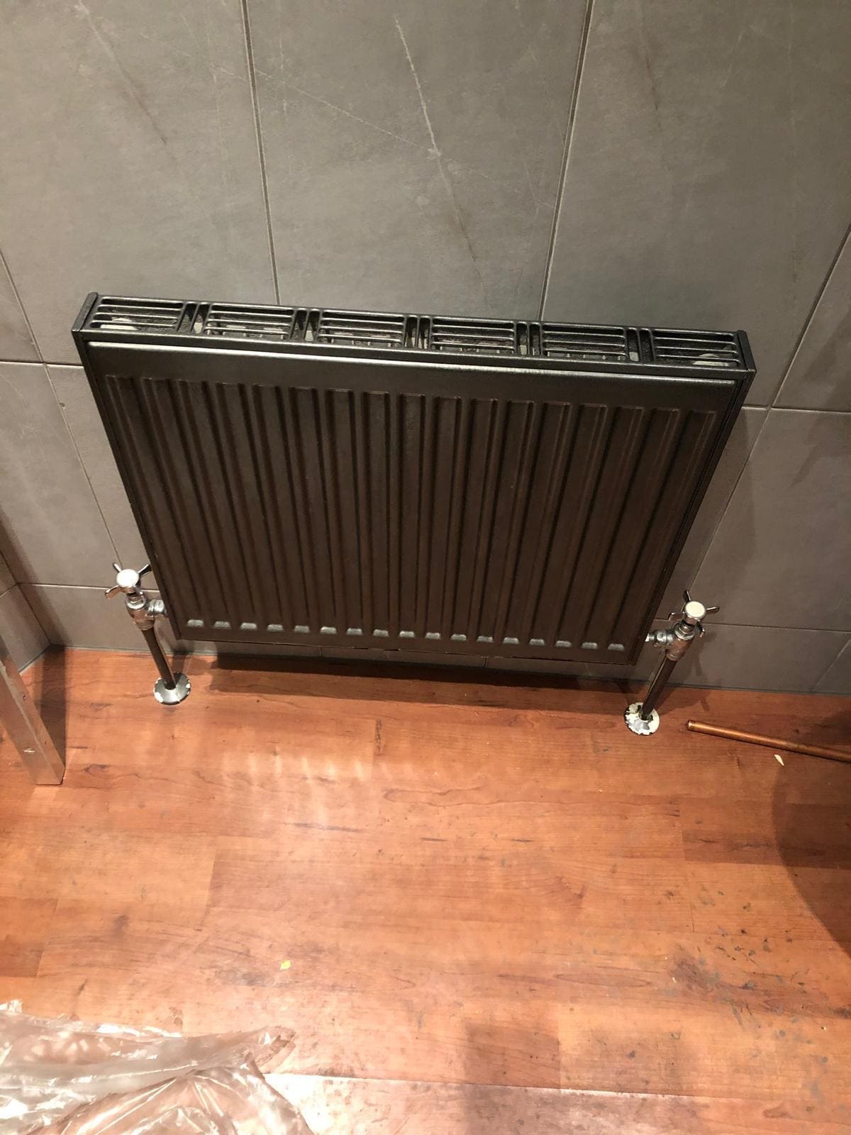 New anthracite panel radiator installed on chrome pipework in a tiled London bathroom by Refurb Squad